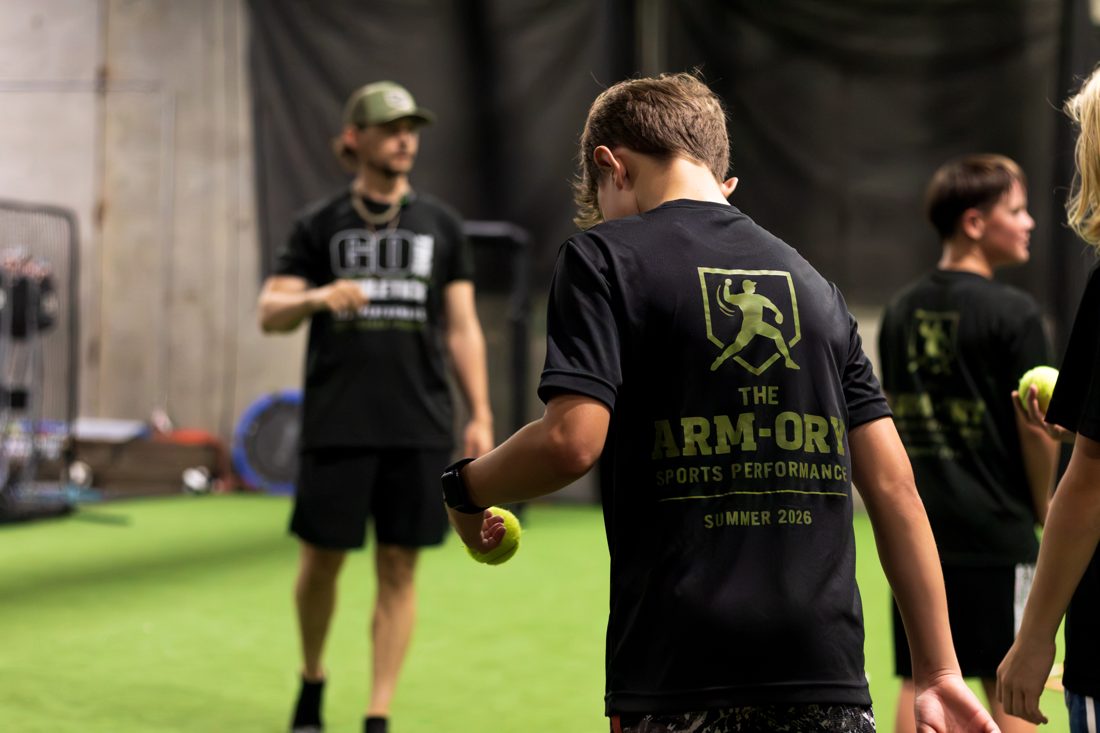 Arm-ory athlete preparing a throwing drill with a coach in the background